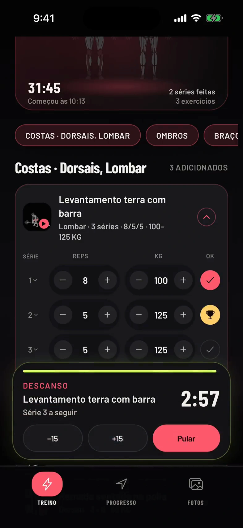 Levantamento terra com barra em um treino em andamento: ao marcar uma série com mais peso que nunca, aparece um troféu dourado com o aviso de novo recorde e o timer de descanso começa